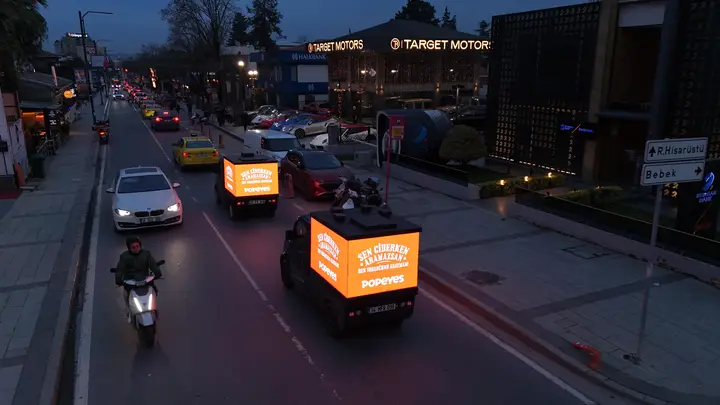 Gece trafiğinde turuncu LED ekranla ilerleyen mini araçlar