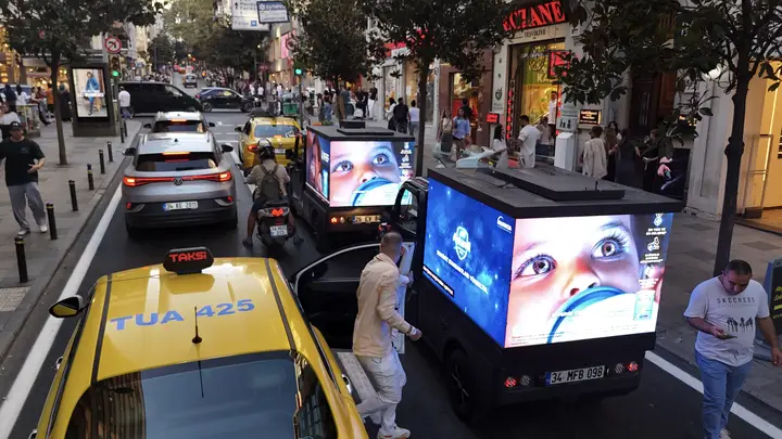 Trafikte taksinin yanında ilerleyen mini LED araç ve yolcular